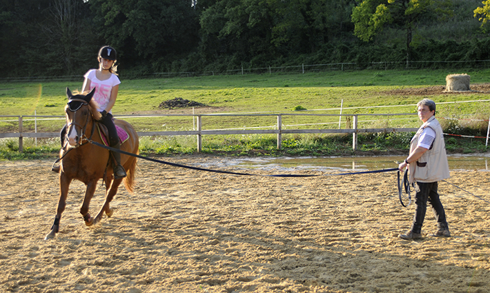 Une monitrice tutore une élève avec son cheval.
